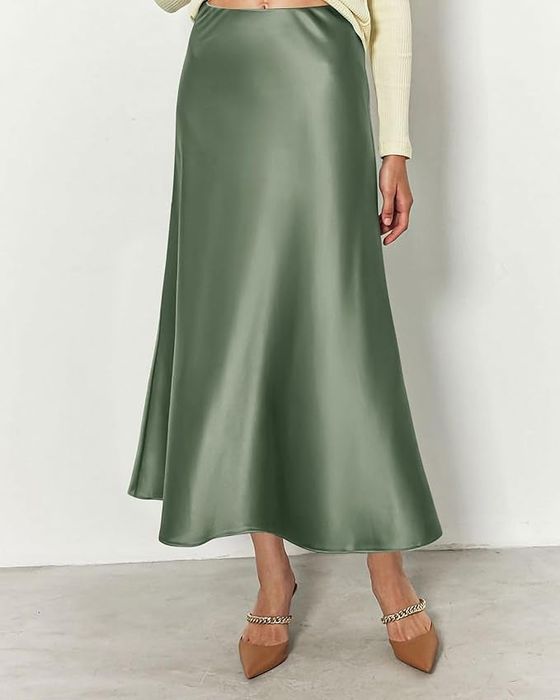 A person wearing a green satin maxi skirt paired with chain-embellished beige heels.
