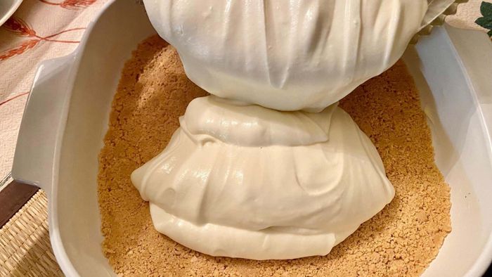 Pouring the creamy cheesecake filling over the prepared crust.