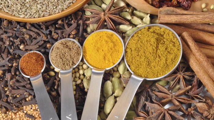A set of measuring spoons loaded with various spices.