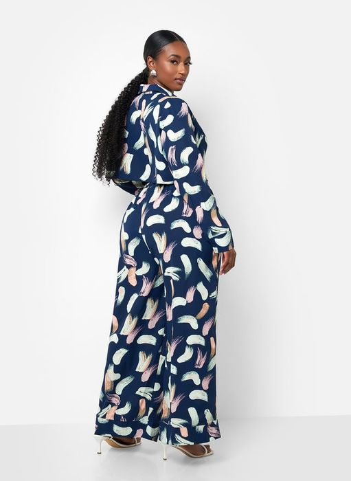 The model strikes a pose in a top and pant set with an abstract print, looking over her shoulder.