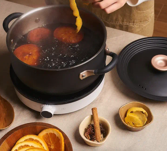 A person making cider in a stockpot.