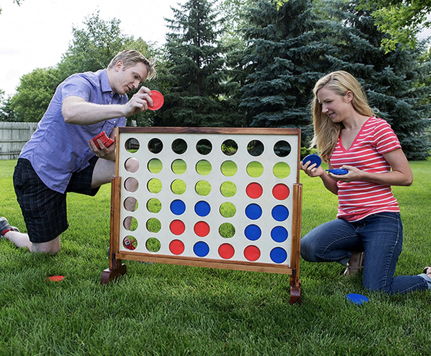 Models enjoy a giant 4 Connect game in their backyard, having fun together.
