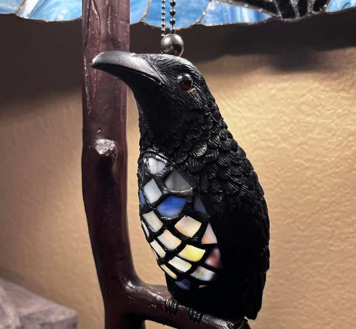 A decorative crow-shaped lamp, featuring a stained-glass body, likely available for purchase.