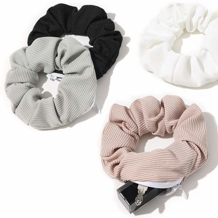 A variety of scrunchies laid out on a table, with one unzipped to reveal a lipstick tube and a key hidden inside.
