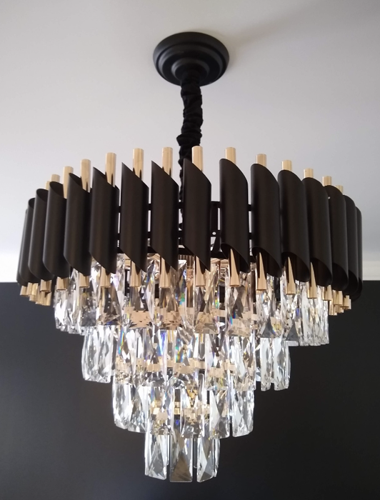Close-up view of a tiered glass chandelier with black and gold accents at the top