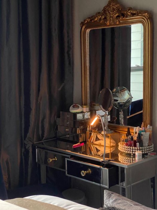 A vanity table featuring a mirror and a collection of beauty products, reflecting a chic and stylish interior