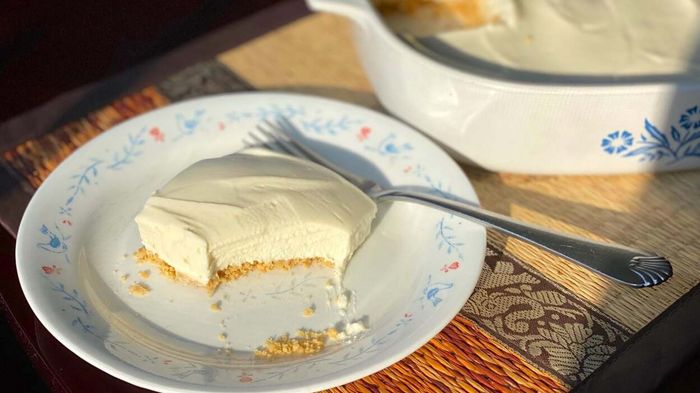 A piece of cheesecake on a plate with a fork beside it.