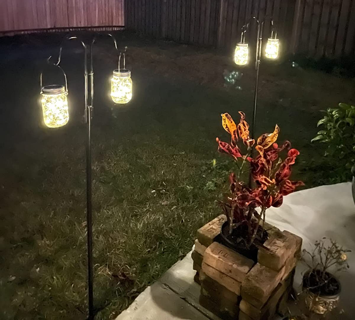 a photo from a customer showing the lanterns hanging on hooks placed in the ground in a backyard