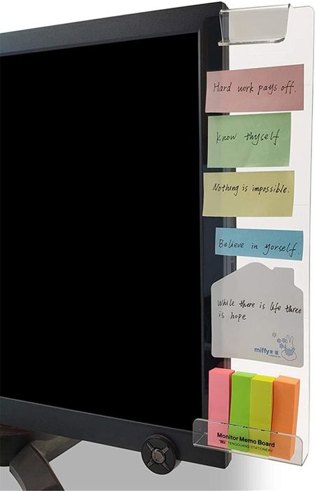 A clear acrylic rectangular attachment on a monitor, adorned with sticky notes