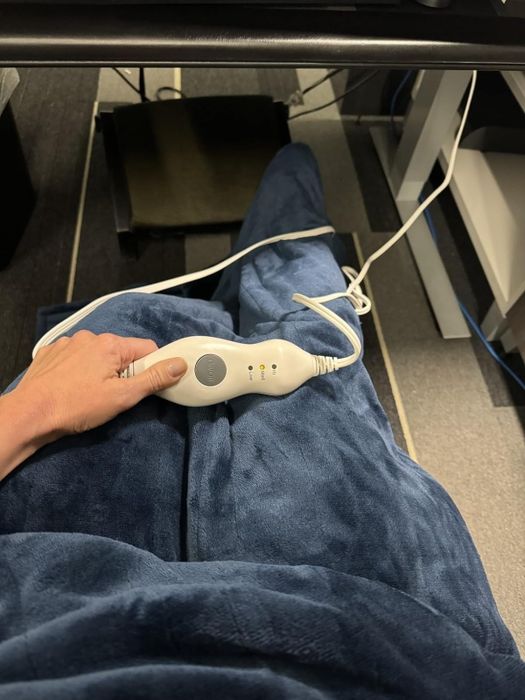 Reviewer cozily wrapped in a heated navy blue throw blanket