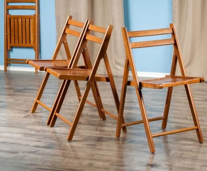 Two wooden chairs facing in opposite directions on a hardwood floor, with a blue wall as the backdrop.