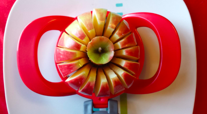 A picture of an apple being neatly cut into 16 uniform slices using the apple cutter.
