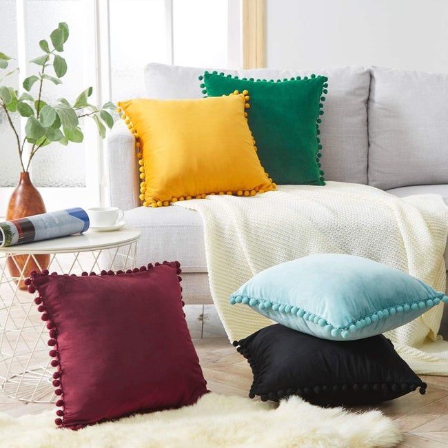 A throw pillow featuring decorative pom-pom borders.