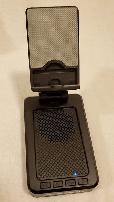 Reviewer photo of a sleek black Bluetooth speaker featuring a built-in phone stand