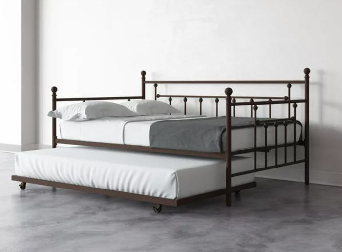 A metal frame bed with a trundle underneath, both featuring simple bedding. No people are present in the image.