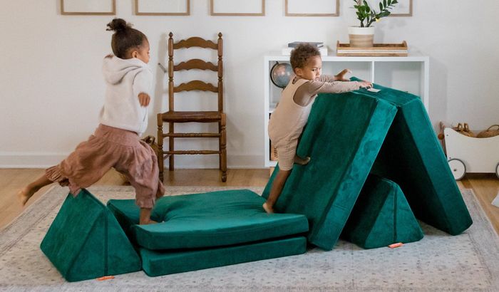 Two children enjoying themselves on a vibrant emerald green Nugget couch.