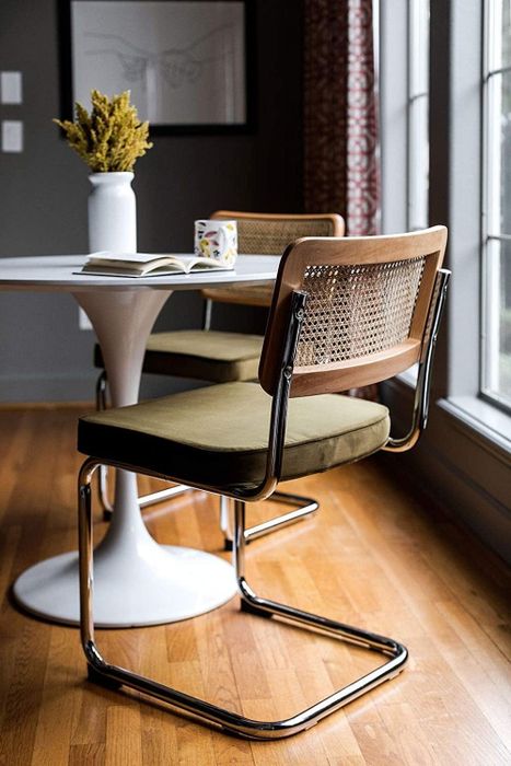 Two contemporary chairs placed at a dining table with a book, near a window in a warm and inviting interior