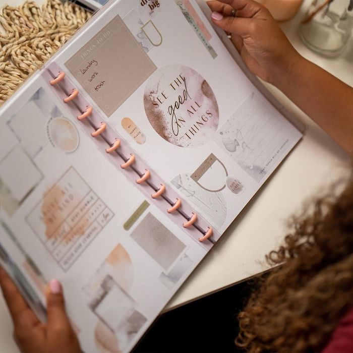 A person holding an open planner adorned with vibrant watercolor stickers