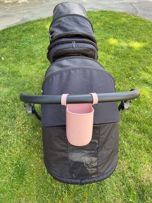 A pink silicone cup holder attached to a stroller