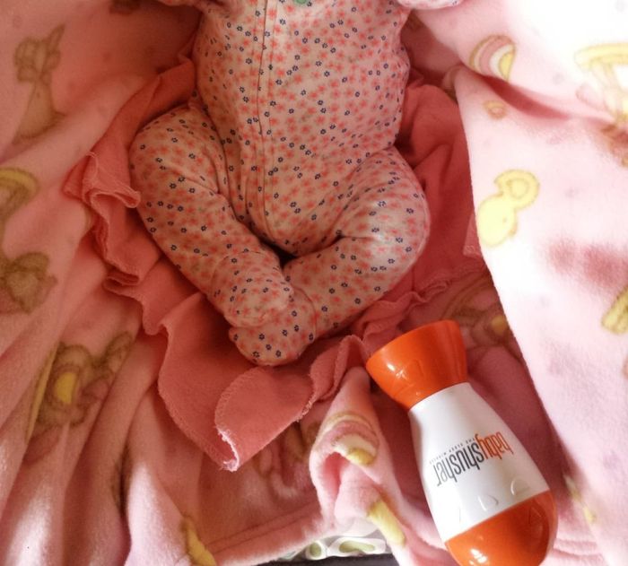 A reviewer shares a moment of their baby peacefully sleeping beside the white noise machine in the bed.