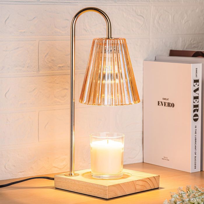 A table lamp featuring a pleated shade and wooden base, paired with a candle and book, creating a cozy, warm glow