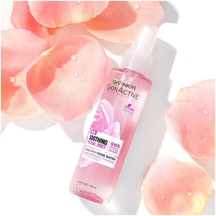 The pink bottle of facial spray surrounded by delicate rose petals