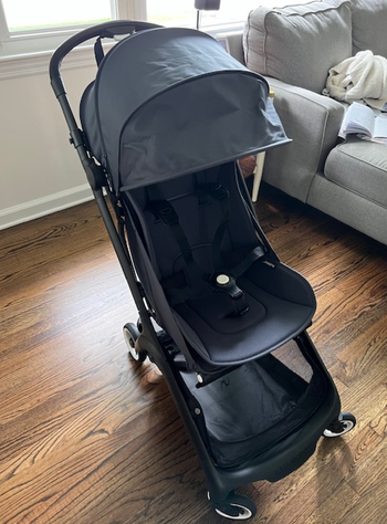 The black Bugaboo Butterfly stroller unfolded on a hardwood floor.