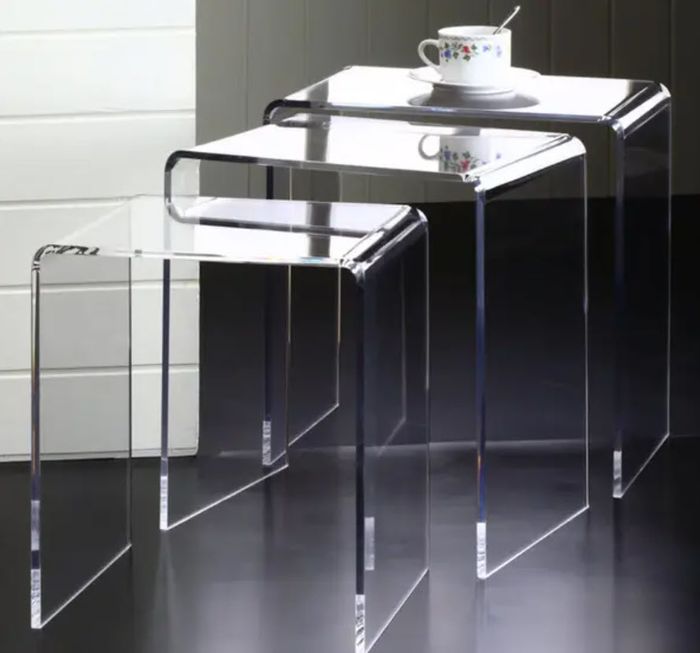 A pair of transparent acrylic nesting tables with a cup and saucer on the top one.