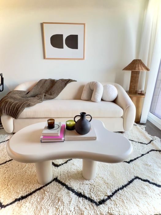 A snug living room arrangement featuring a sofa, a coffee table with a teapot and cup set, and a stylish patterned rug