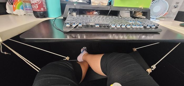Reviewer comfortably resting their feet on a desk-sized foot hammock