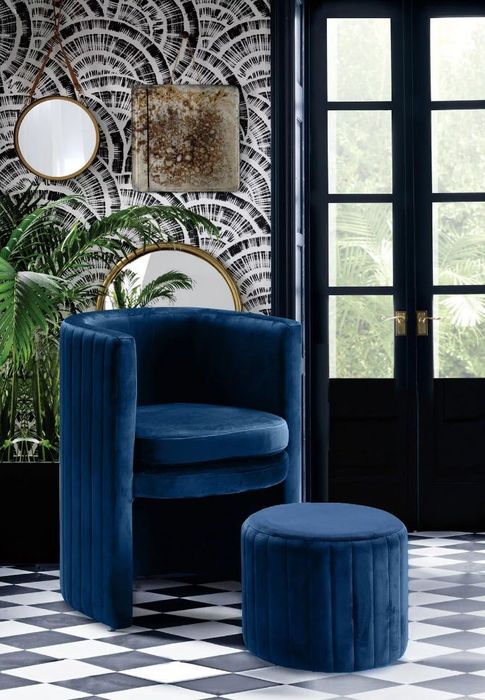A plush blue chair paired with a matching ottoman, set in a chic room with checkered floors and decorative mirrors