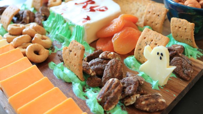 A charcuterie board featuring cheese sculpted into ghost shapes.