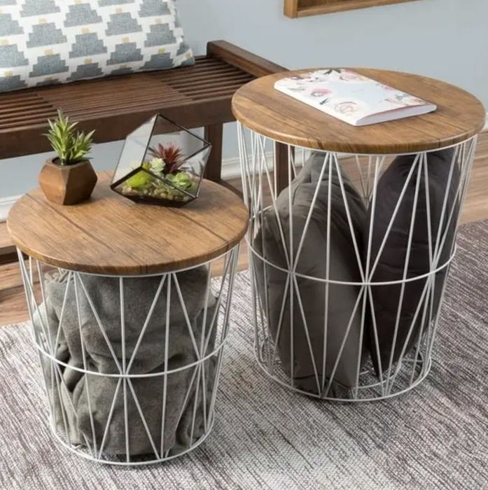 Two round side tables with wooden tops and geometric metal bases, one adorned with a plant and magazines, adding both function and style to the space.