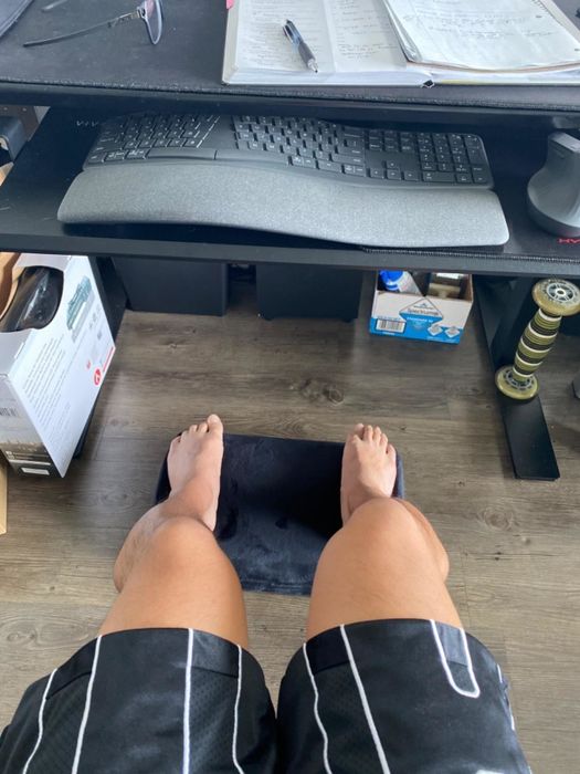 Reviewer's perspective of feet resting on a footrest beneath a home office desk
