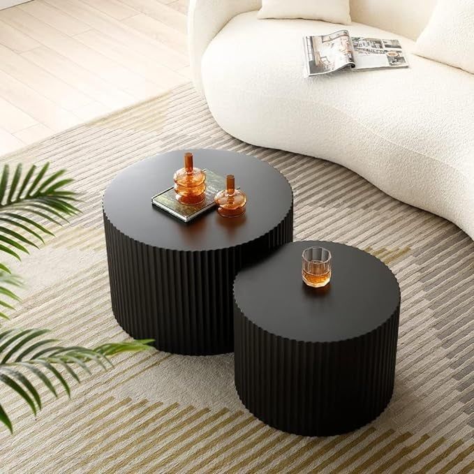 Two round, textured coffee tables adorned with decorative items in a modern living area