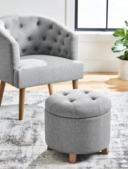 A grey tufted armchair paired with a matching ottoman, set in a well-lit room.
