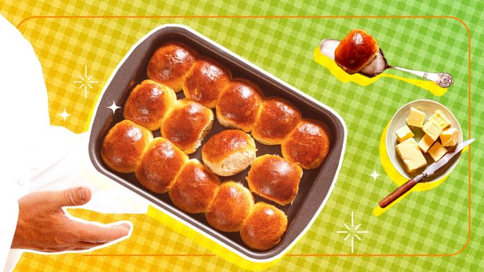 A person serving dinner rolls in a casserole dish with a green backdrop.