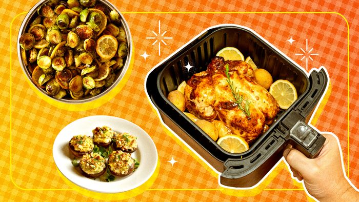 An air fryer basket holding a roasted chicken, with a plate of vegetables floating beside it.
