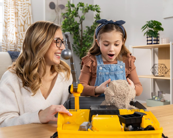 A woman and child happily playing with kinetic sand at a table