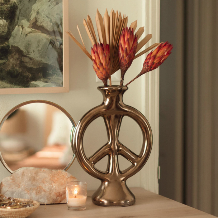The bronze peace sign-shaped vase displayed on a table