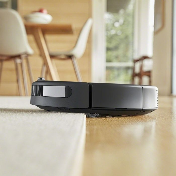 A flat, round vacuum transitioning from a rug to a wood floor.