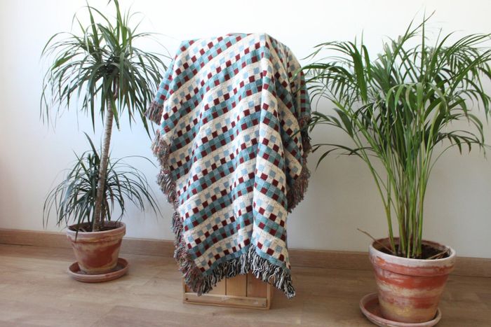 A checkered throw blanket casually draped over a tall stool