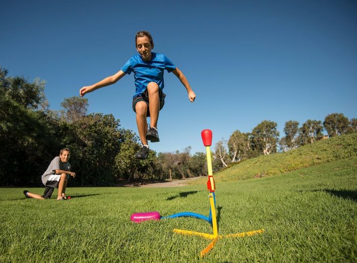 A child jumping on a foam rocket launcher in a park