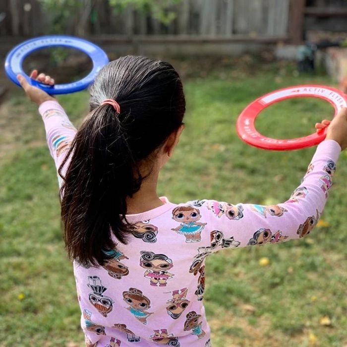 a reviewer showing their child holding red and blue flying rings in the yard