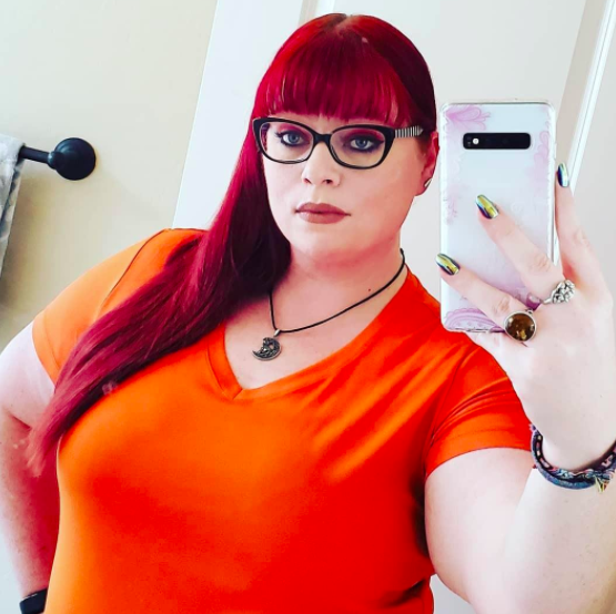 Reviewer snapping a selfie in an orange moisture-wicking tee