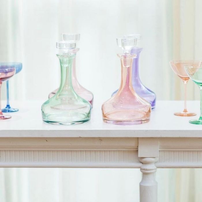 An assortment of elegant glassware, including decanters and delicate stemmed glasses, neatly arranged on a white railing.