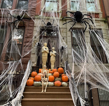 spider web decoration draped over the front stoop of a brownstone apartment