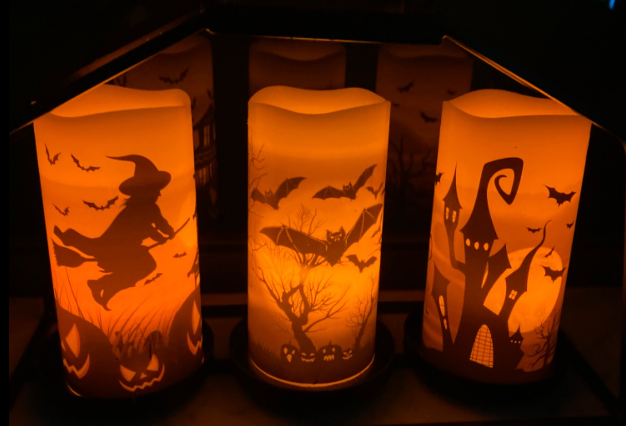 three Halloween-themed candles displayed on a reviewer’s bookshelf