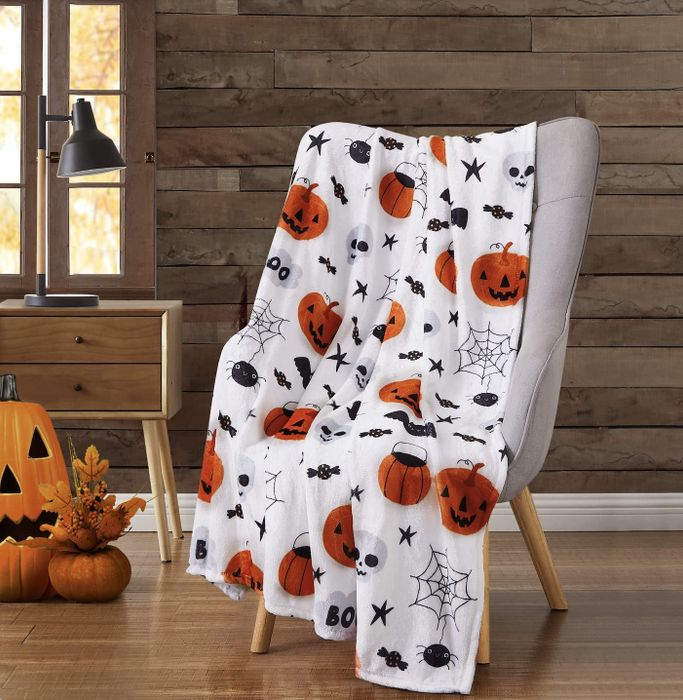 soft blanket featuring pumpkins, spiders, and skulls on the front
