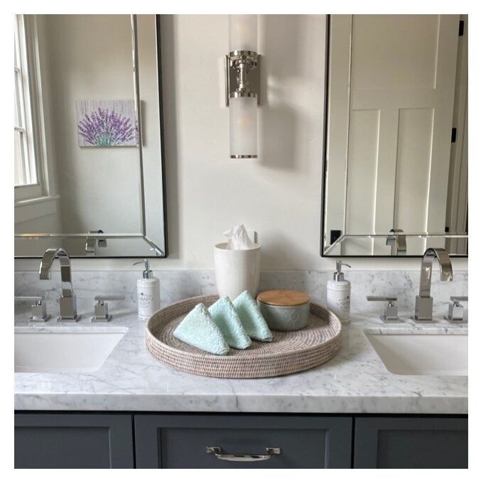 The circular rattan tray sitting on a bathroom vanity, elegantly holding towels in place.